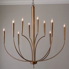 a chandelier with many lit candles hanging from it's center point in a room