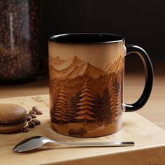 a coffee mug sitting on top of a wooden table next to a spoon and cookie