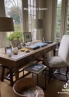 an office with a desk and chairs in front of two large windows that look out onto the woods