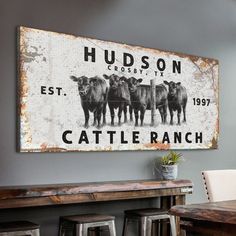 an old metal sign hangs on the wall above a wooden table with stools in front of it