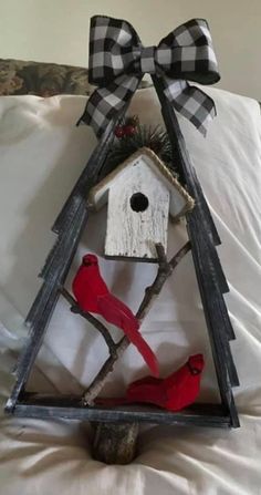 a birdhouse with two red birds on it and a bow hanging from the roof