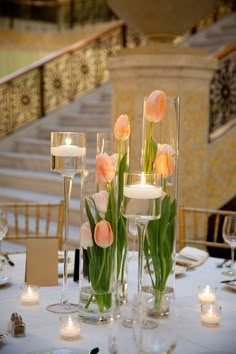 flowers in vases on a table with candles and place settings for the tables to be set