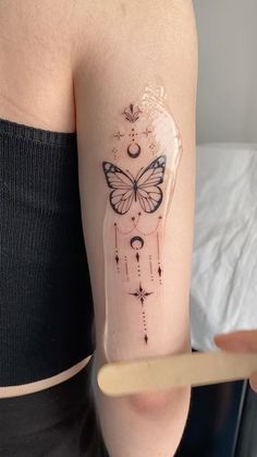 a woman's arm with a butterfly tattoo on it, and an arrow in the middle