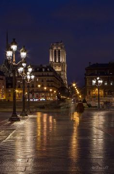 an empty city street at night with lights on and buildings in the backgroud