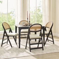 a dining room table with four chairs and a rug on the floor in front of it