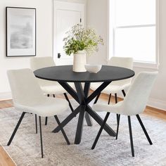 a black table with white chairs and a vase on top