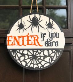 a sign that says enter if you dare hanging from a door with spider webs on it