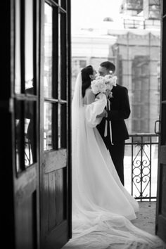 a bride and groom kissing in front of an open door