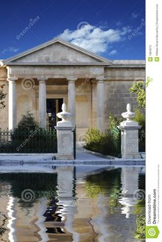 an old building with columns and pillars reflected in the water