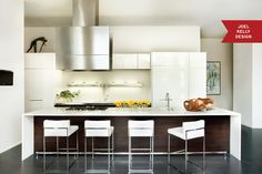 modern kitchen with white cabinets and stainless steel counter tops, bar stools, and center island