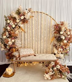 a bench with flowers and candles in front of a white backdrop that has vertical striped drapes