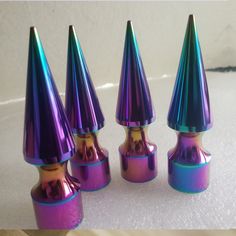 three shiny purple and blue cones sitting on top of a white countertop next to each other