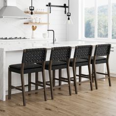 four chairs are lined up in front of an island with marble countertops and white walls