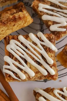 several pieces of dessert sitting on top of a cooling rack next to cinnamon stick sticks