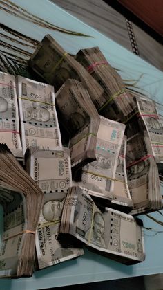 a pile of twenty dollar bills sitting on top of a blue tablecloth covered counter