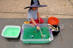 a little boy in a witches hat is playing with green liquid and other items on the ground