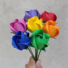 a hand holding a bunch of multicolored paper roses