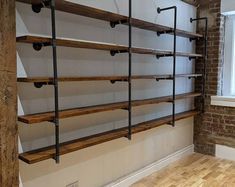 an empty room with some shelves on the wall and wood floors in front of it