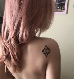 a woman with pink hair has a tattoo on her back