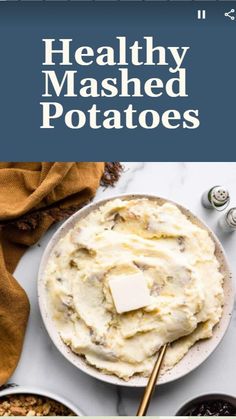 mashed potatoes in a bowl with butter and seasoning on the side next to other dishes