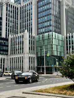 cars are driving down the street in front of tall buildings with glass panels on them