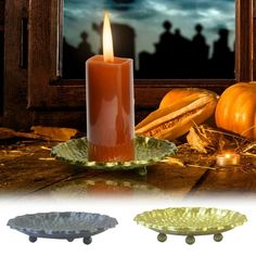 an orange candle sitting on top of a table next to two plates with pumpkins