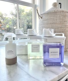 several different types of soaps and bottles on a counter in front of a window