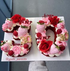 a person holding up a cake shaped like the number 50 with flowers and berries on it