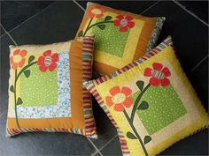 three decorative pillows with flowers on them sitting on a tile floor next to each other