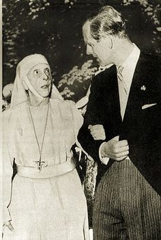 an old photo of two people talking to each other in front of a man wearing a nun costume