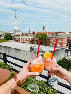 two people toasting with drinks on top of a building