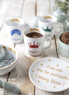 coffee cups and saucers on a wooden table with christmas decorations in the back ground