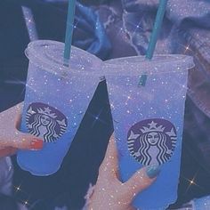 two people holding up starbucks cups with straws in their hands and glitter on them