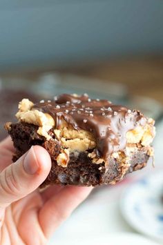 a hand holding up a chocolate cookie with peanut butter on it and sprinkled in chocolate