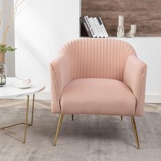 a pink chair sitting on top of a rug next to a white table and vase