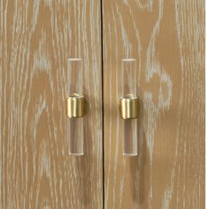 a wooden cabinet with two glass doors and gold handles