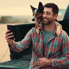 a man holding a dog in his arms while standing next to a truck with the bed open