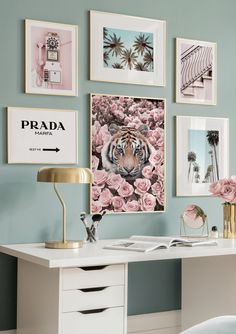 a white desk with pink flowers and pictures on the wall above it in a bedroom