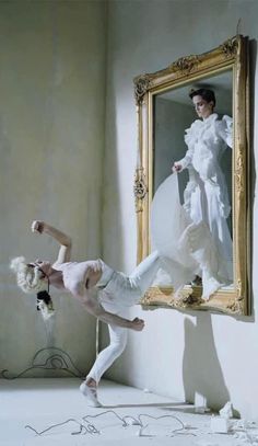 the woman is dancing in front of a mirror with one leg up and her other hand behind her head