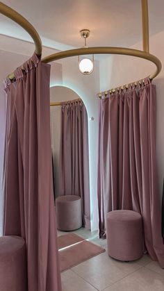 a room with pink curtains and round stools