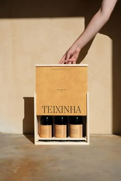 a person reaching into a box with three bottles in it that are labeled texinha