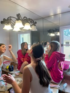 a group of young women standing in front of a mirror