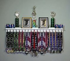 a bunch of medals are hanging on a wall above a rack with two framed pictures