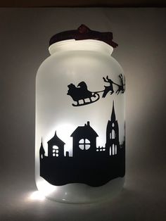 a glass jar with a silhouette of santa claus on his sleigh