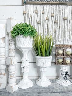 three white vases with plants in them sitting on a table next to other decorative items