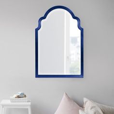 a mirror on the wall above a bed in a room with white walls and pillows