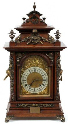 an ornate wooden clock with gold trimmings and carvings on the face, sitting against a white background