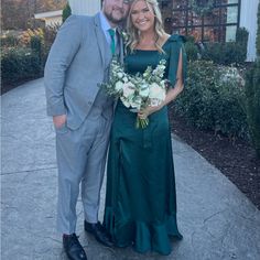 a man and woman standing next to each other in front of a building with flowers