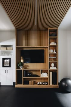 a room with a large wooden shelf and black ball on the floor next to it