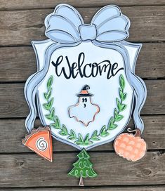 a welcome sign on the side of a wooden wall with ornaments around it and a bow